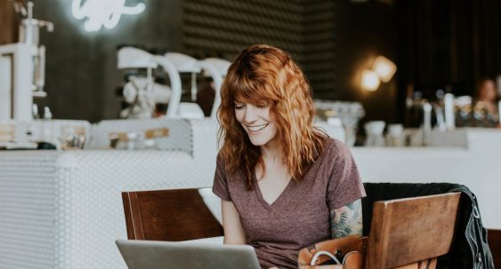 jeune femme souriante dans un café travaillant sur un ordinateur portable